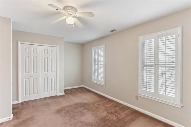 unfurnished bedroom featuring baseboards, visible vents, ceiling fan, a closet, and carpet flooring