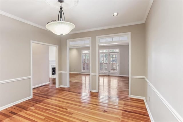 unfurnished dining area with light wood finished floors, a fireplace, and ornamental molding