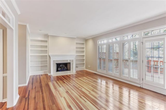 unfurnished living room with light wood-style flooring, a fireplace, and ornamental molding