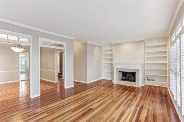 unfurnished living room featuring light wood-type flooring, baseboards, ornamental molding, and a fireplace