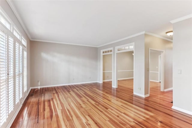 empty room with crown molding, light wood-style floors, baseboards, and visible vents