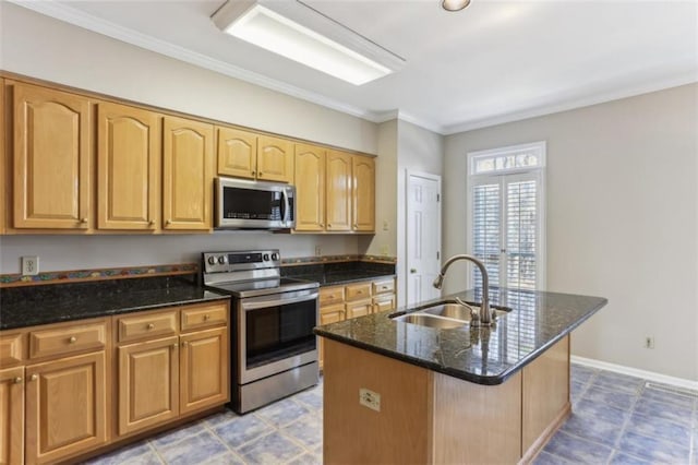 kitchen featuring an island with sink, a sink, stainless steel appliances, dark stone counters, and baseboards