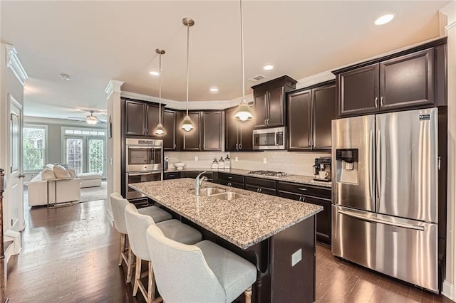 2433 Santa Rosa St, Alpharetta, GA 30009 - kitchen with stainless steel appliances, a kitchen bar, light stone counters, dark brown cabinets, and a center island with sink