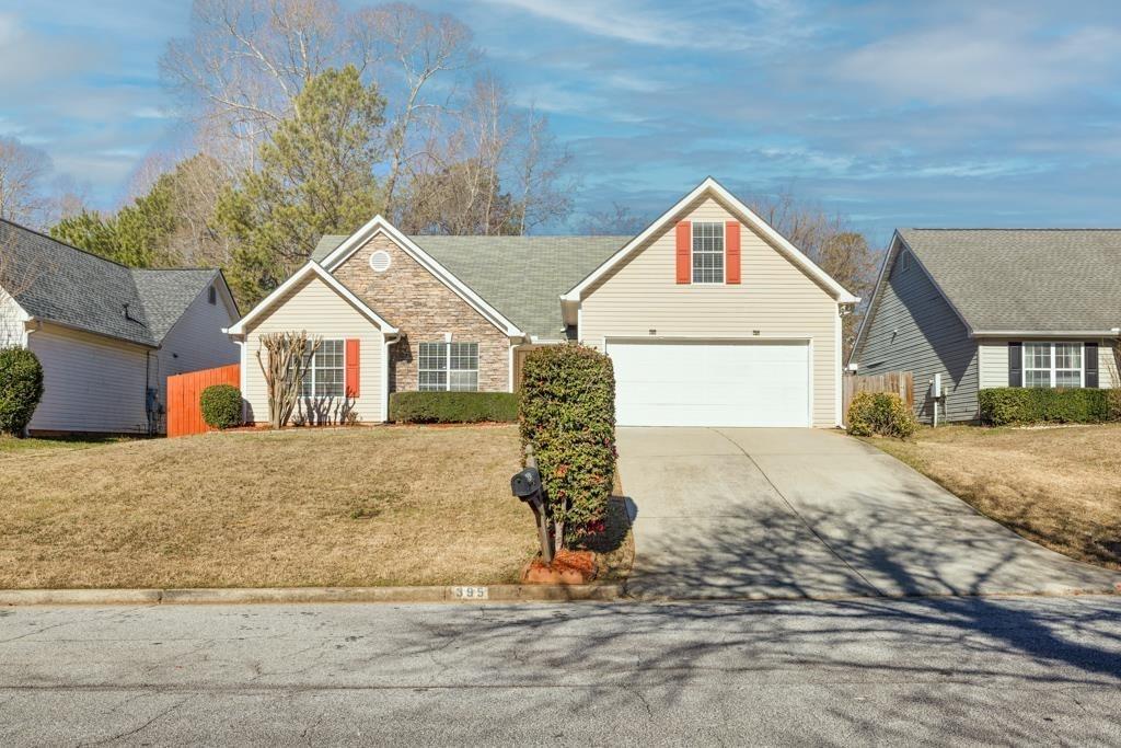 395 Shadetree Ln, Lawrenceville, GA 30044 - view of front of property with a garage, a front yard, stone siding, and driveway