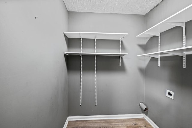 clothes washing area featuring a textured ceiling, laundry area, wood finished floors, baseboards, and electric dryer hookup