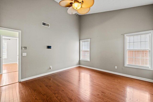 spare room with visible vents, a healthy amount of sunlight, hardwood / wood-style flooring, and baseboards