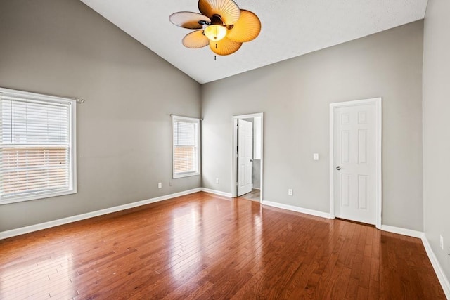 spare room with high vaulted ceiling, a ceiling fan, hardwood / wood-style flooring, and baseboards