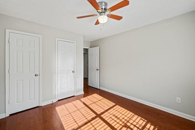 unfurnished bedroom featuring ceiling fan, baseboards, and dark wood finished floors