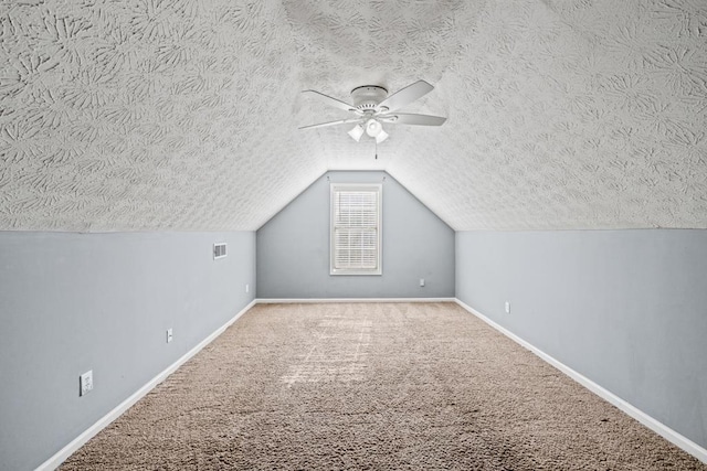 additional living space with lofted ceiling, carpet, baseboards, and a textured ceiling