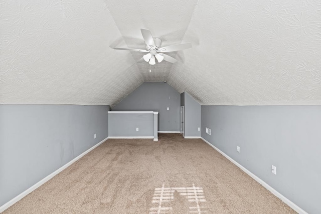 bonus room featuring lofted ceiling, carpet flooring, a textured ceiling, and baseboards