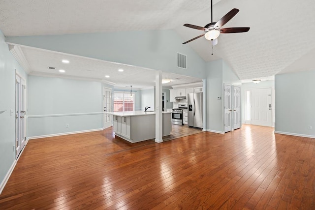 unfurnished living room with visible vents, ceiling fan, high vaulted ceiling, baseboards, and hardwood / wood-style flooring