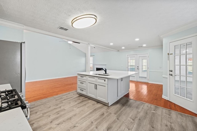 kitchen featuring french doors, gas range oven, visible vents, freestanding refrigerator, and a sink