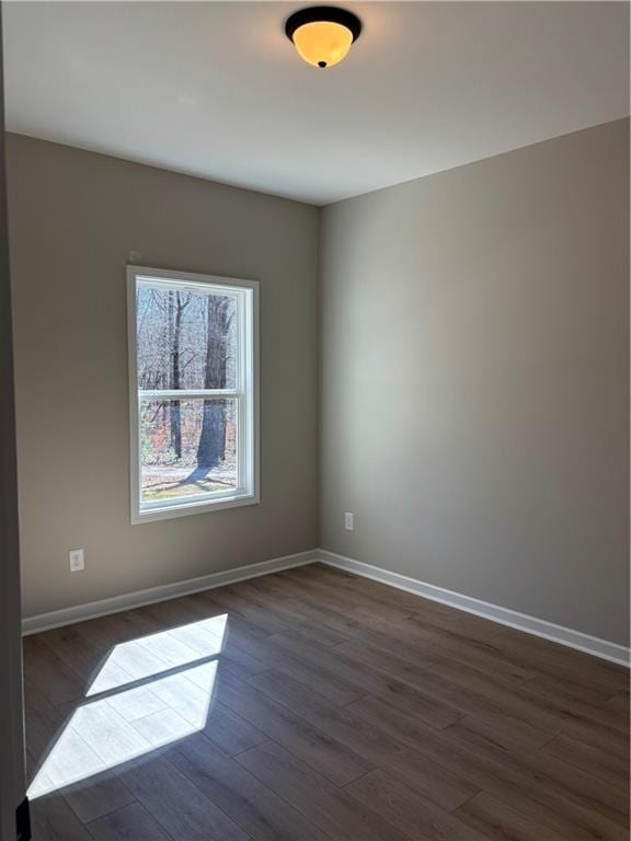 spare room featuring dark wood finished floors and baseboards