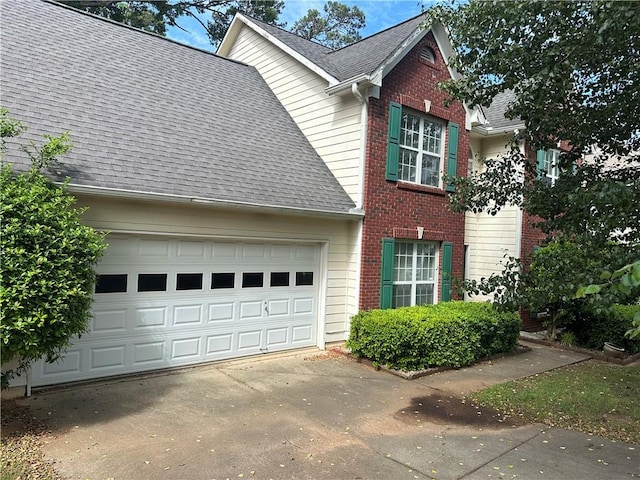 1570 Twin Bridge Ln, Lawrenceville, GA 30043 - view of home's exterior featuring driveway, brick siding, roof with shingles, and an attached garage