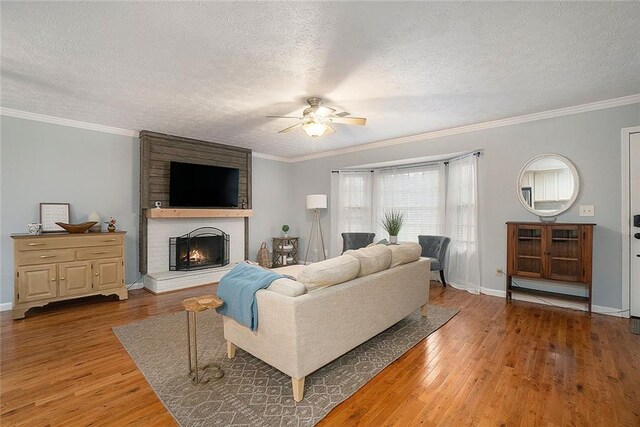 living room with wood-type flooring, a textured ceiling, a brick fireplace, and ceiling fan