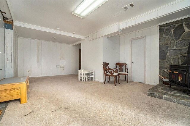 basement featuring a wood stove, carpet floors, and ornamental molding