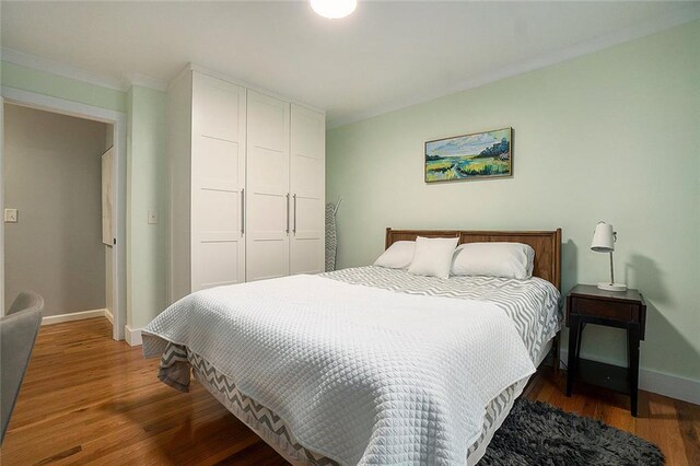 bedroom with dark hardwood / wood-style flooring, a closet, and ornamental molding