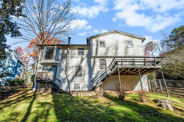 rear view of house featuring a lawn and a wooden deck