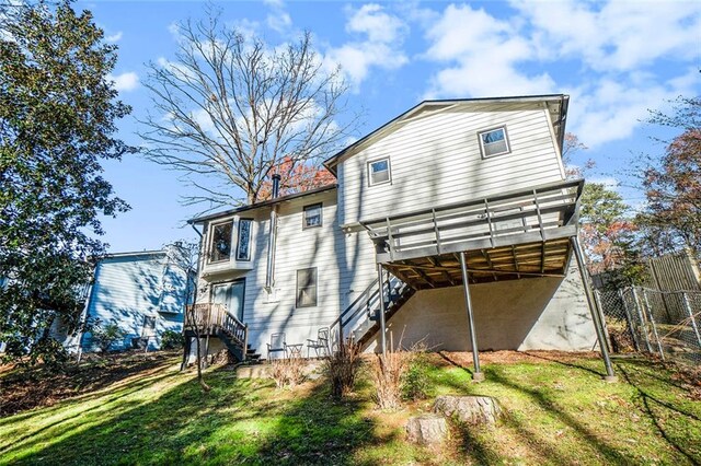 rear view of house featuring a deck and a lawn