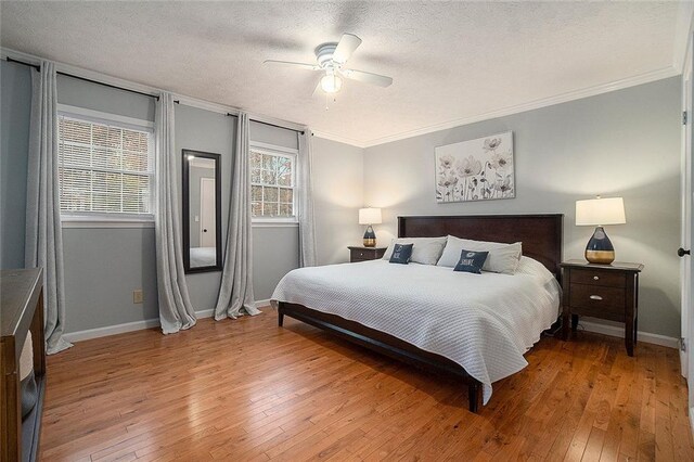 bedroom with ceiling fan, crown molding, wood-type flooring, and a textured ceiling