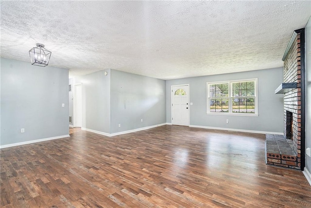 96 S Forty Pass S, Hiram, GA 30141 - unfurnished living room with a brick fireplace, wood finished floors, a textured ceiling, and a chandelier