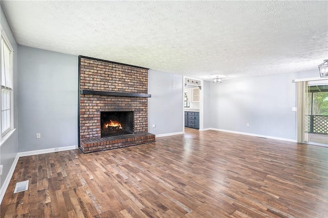 96 S Forty Pass S, Hiram, GA 30141 - unfurnished living room featuring a textured ceiling, wood finished floors, and a brick fireplace