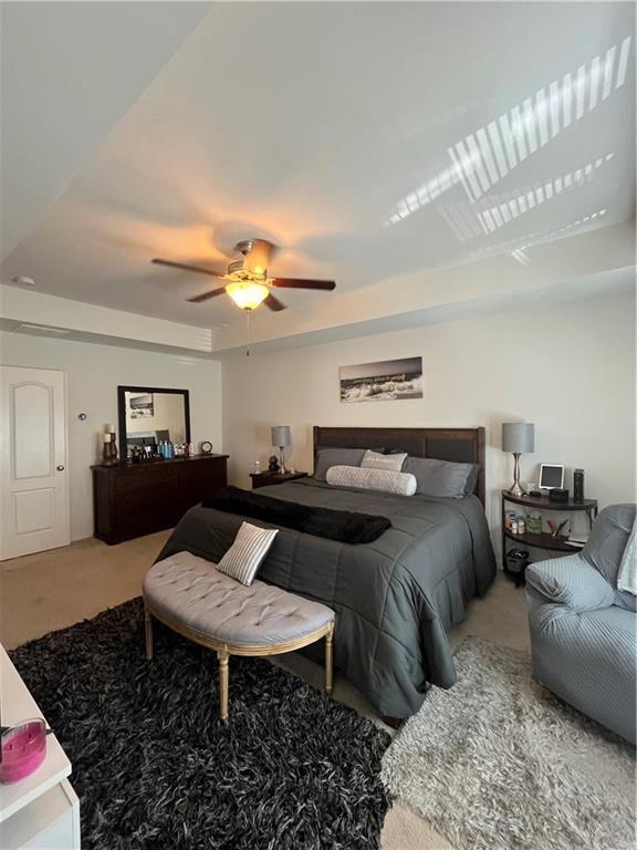 7699 Cabrini Pl, Fairburn, GA 30213 - carpeted bedroom with a tray ceiling and ceiling fan
