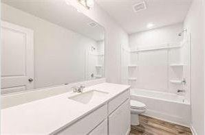 bathroom with shower / bath combination, vanity, toilet, and wood finished floors