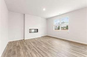 unfurnished living room with a glass covered fireplace and wood finished floors