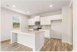 kitchen with stainless steel appliances, light countertops, white cabinets, and wood finished floors