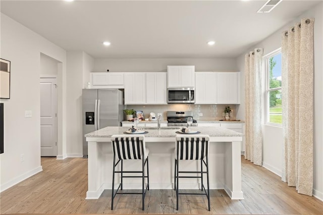 kitchen with stainless steel appliances, light countertops, white cabinets, and wood finished floors