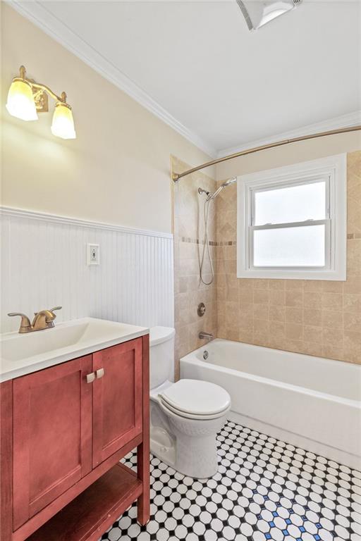 full bathroom with ornamental molding, vanity, tiled shower / bath, and toilet