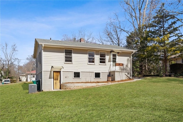 rear view of house featuring central air condition unit and a yard