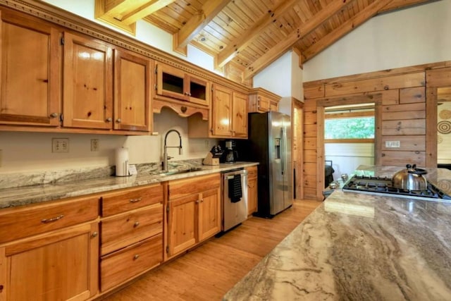 kitchen featuring beamed ceiling, a sink, light stone counters, appliances with stainless steel finishes, and wood ceiling