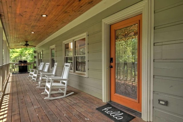 wooden deck featuring a ceiling fan, covered porch, and a grill