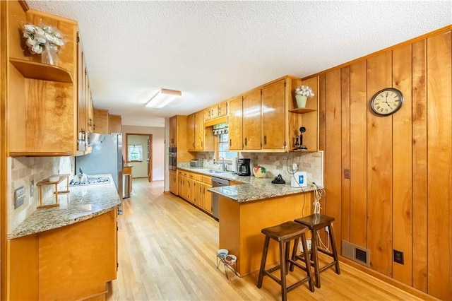 5670 Lanny Dr, Powder Springs, GA 30127 - kitchen with open shelves, brown cabinetry, tasteful backsplash, light wood finished floors, and a textured ceiling