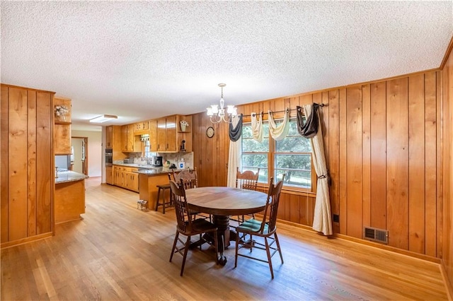 5670 Lanny Dr, Powder Springs, GA 30127 - dining space with a chandelier, light wood-style flooring, a textured ceiling, and wood walls