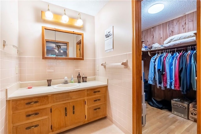 5670 Lanny Dr, Powder Springs, GA 30127 - bathroom featuring vanity, tile walls, ceiling fan, a walk in closet, and wood finished floors
