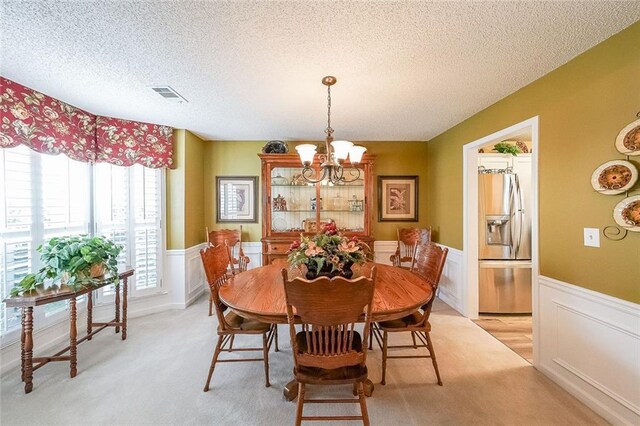 626 Dahoma Trl, Woodstock, GA 30188 - dining room featuring a chandelier, a textured ceiling, a wainscoted wall, and light carpet