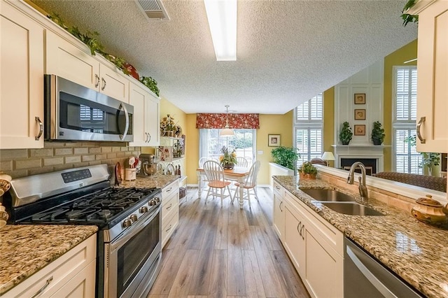 626 Dahoma Trl, Woodstock, GA 30188 - kitchen with appliances with stainless steel finishes, a textured ceiling, a sink, wood finished floors, and light stone counters