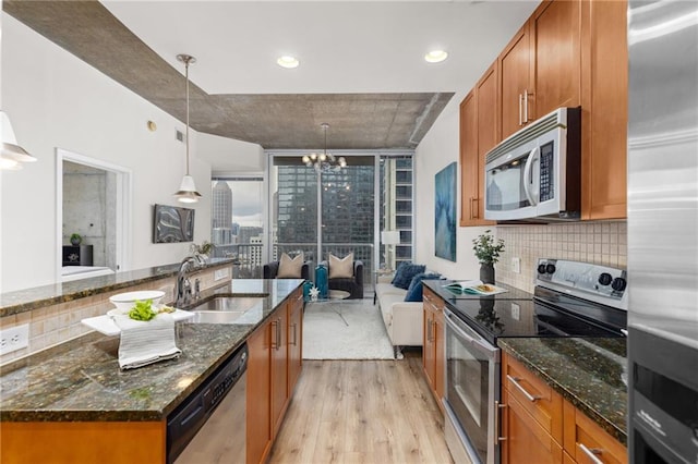 kitchen featuring pendant lighting, an island with sink, dark stone countertops, and appliances with stainless steel finishes