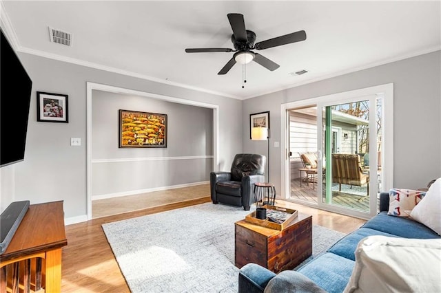 living room featuring crown molding, ceiling fan, and light wood-type flooring