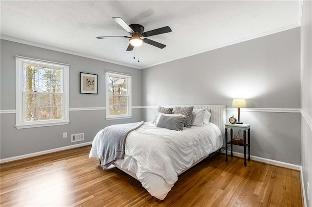 bedroom featuring hardwood / wood-style flooring, ornamental molding, and ceiling fan