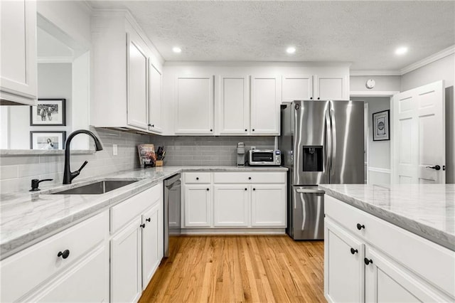 kitchen featuring light stone counters, stainless steel appliances, sink, and white cabinets