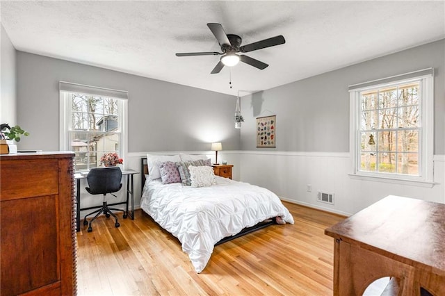 bedroom with a textured ceiling, wood-type flooring, and ceiling fan