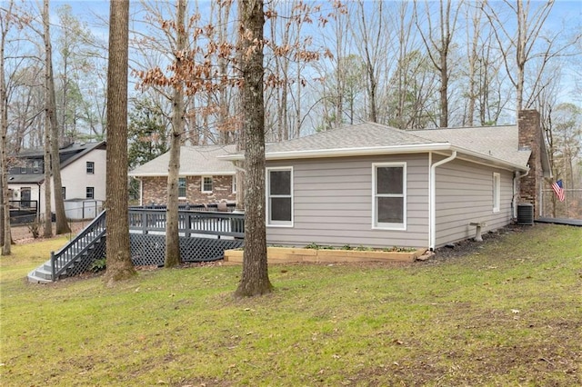 rear view of house featuring a wooden deck, cooling unit, and a lawn