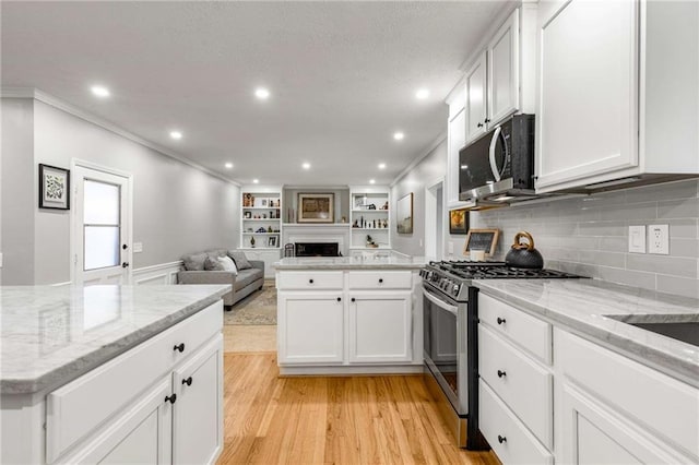 kitchen featuring crown molding, stainless steel gas range, light hardwood / wood-style floors, and white cabinets