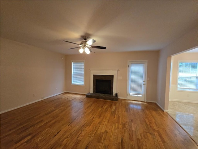 unfurnished living room featuring ceiling fan, hardwood / wood-style floors, and a fireplace