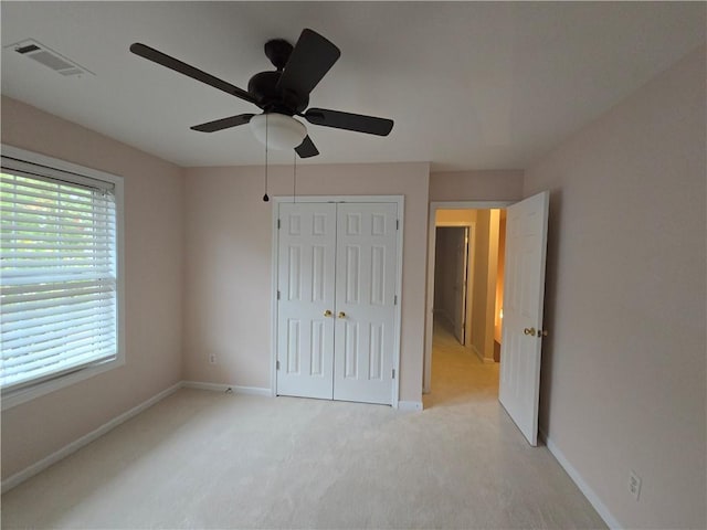 unfurnished bedroom featuring light colored carpet, a closet, and ceiling fan