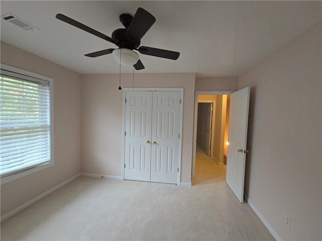 unfurnished bedroom with ceiling fan, light colored carpet, and a closet